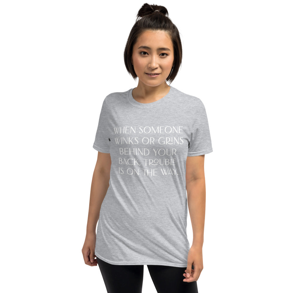 Unisex soft-style sport grey T-shirt with WHEN SOMEONE WINKS OR GRINS BEHIND YOUR BACK, TROUBLE IS ON THE WAY in White letters
