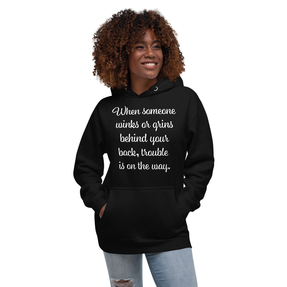 Black Unisex Premium Hoodie with When someone winks or grins behind your back, trouble is on the way.